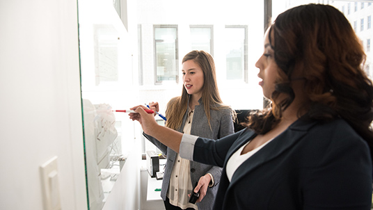 Two work colleagues having a discussion at a whiteboard