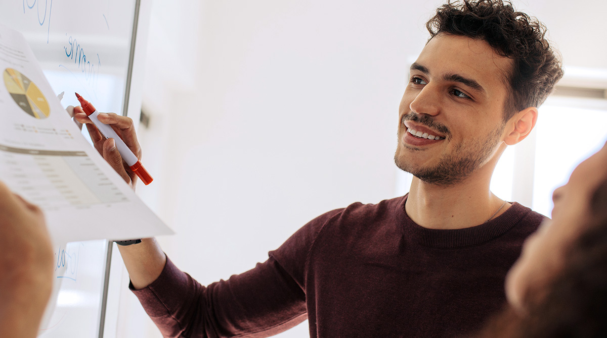 Man in office, working at whiteboard with co-workers