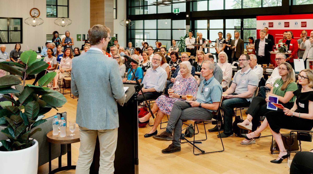 Seated crowd looking at man at lectern